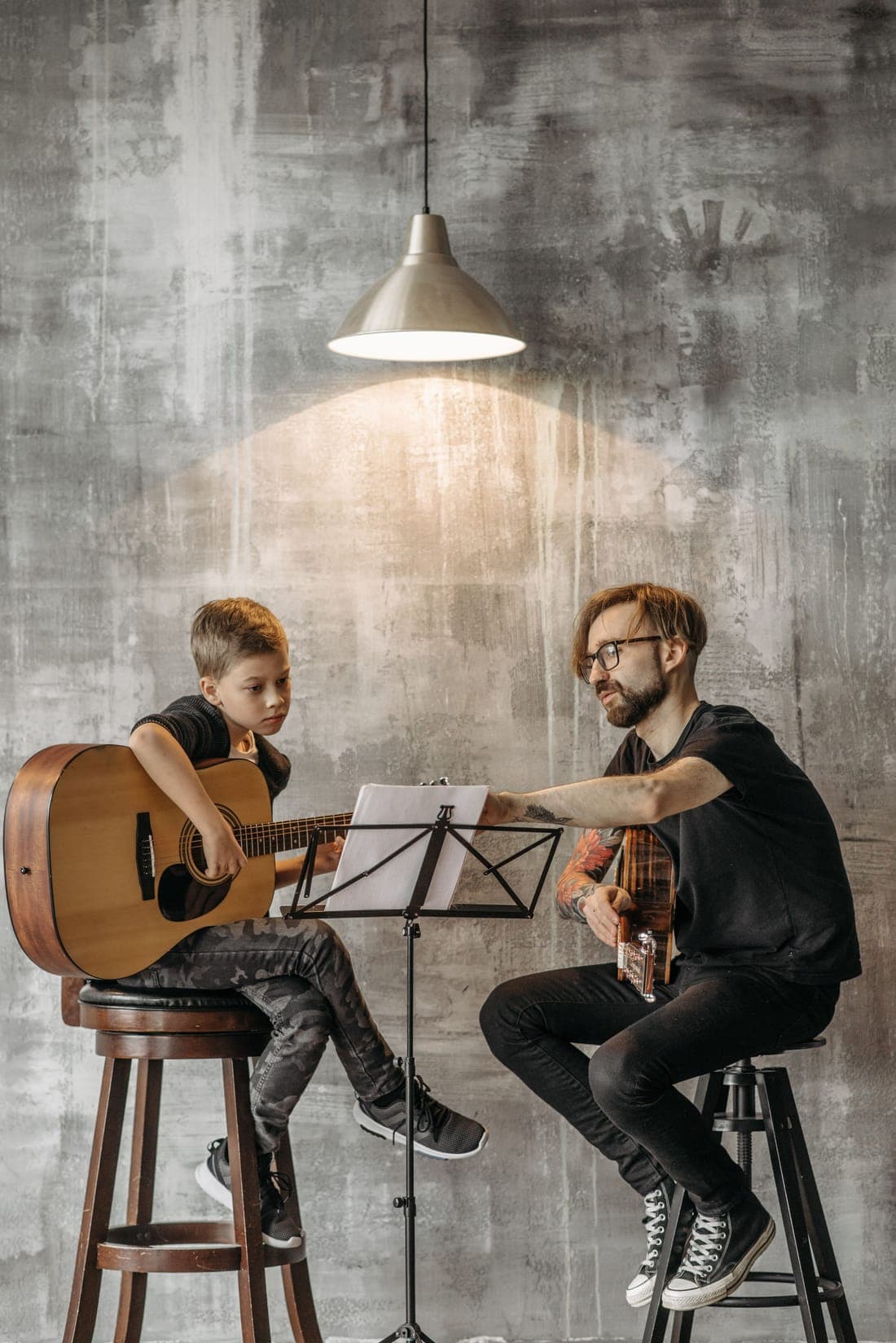 A guitar teacher and young student playing from a music stand