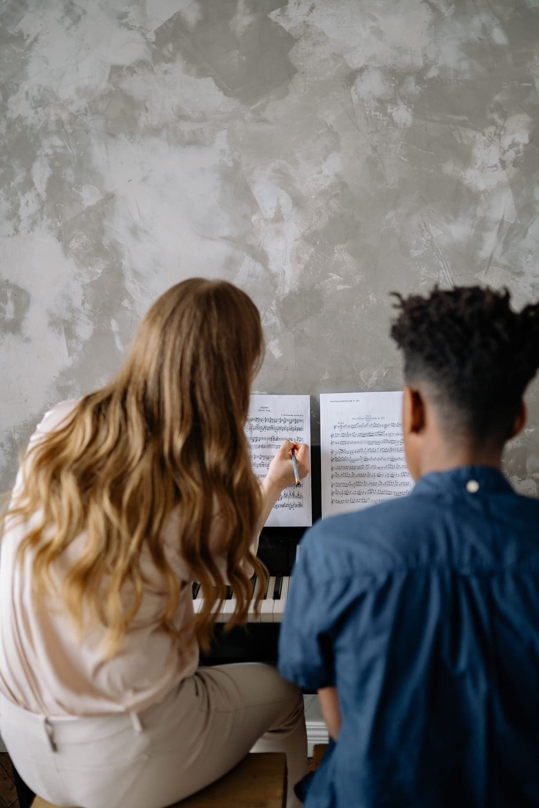 A teacher pointing out a passage of sheet music to a student