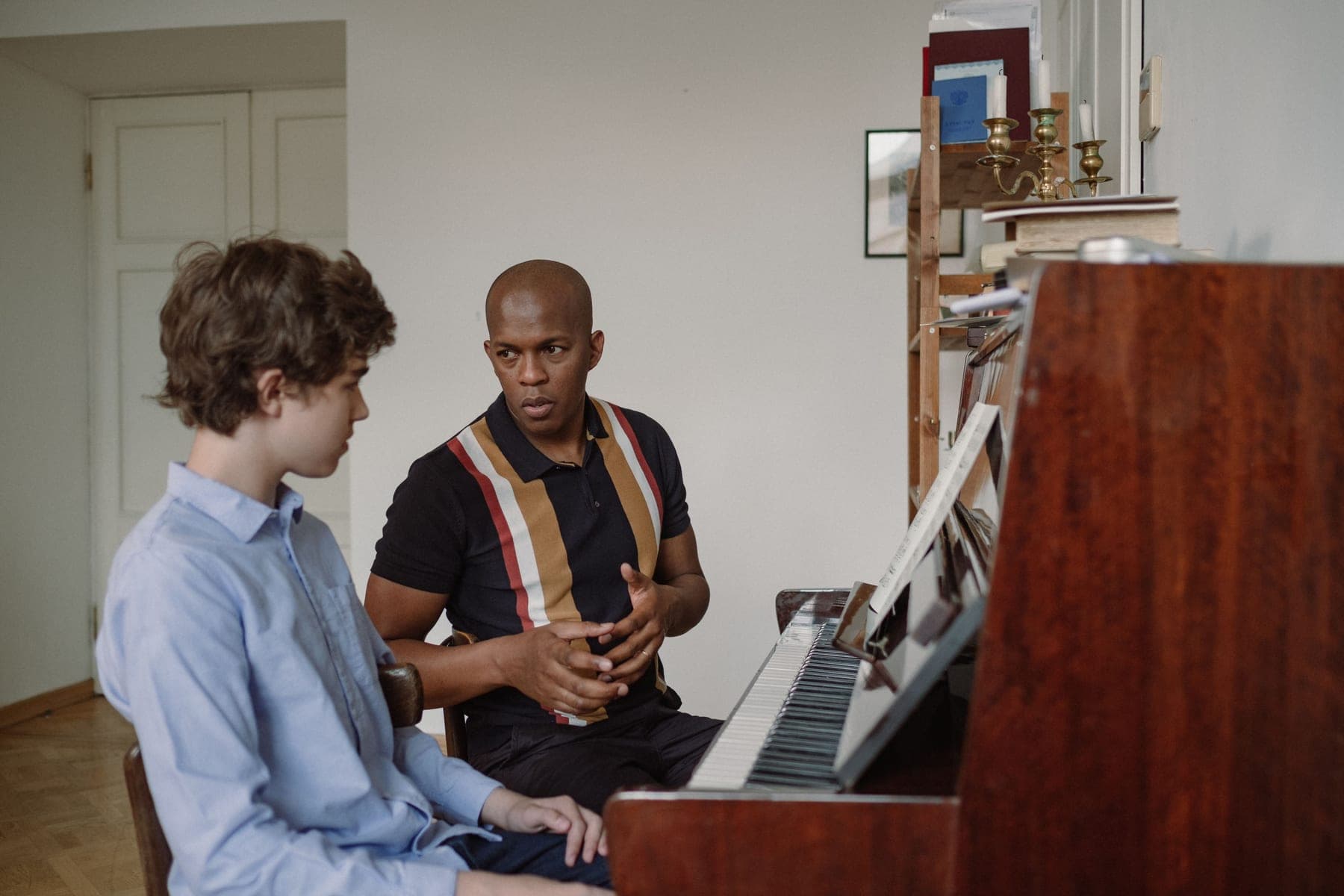 A teacher guiding a young student through a piano lesson at home